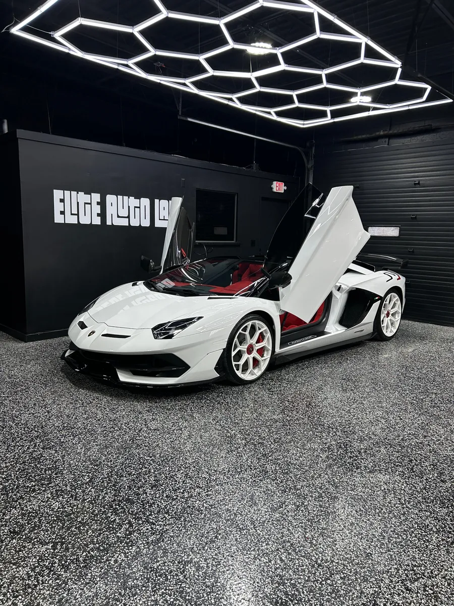 White Lamborghini Aventador with its doors raised in the Elite Auto Lab shop in Madison Heights, a paint protection film job